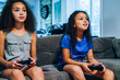 © Inti St. Clair - Girls playing video games together on couch