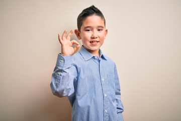 Poster - Young little boy kid wearing elegant shirt standing over isolated background smiling positive doing ok sign with hand and fingers. Successful expression.