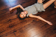 © Inti St. Clair - Smiling girl laying on wood floor in home