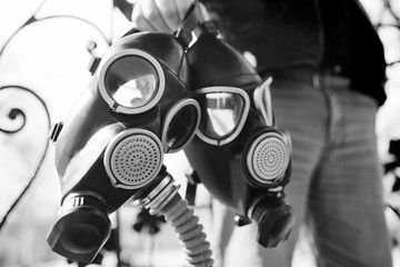 a man is holding two black gas masks in close-up. Radiation, nuclear explosion, Apocalypse, coronavirus, covid19