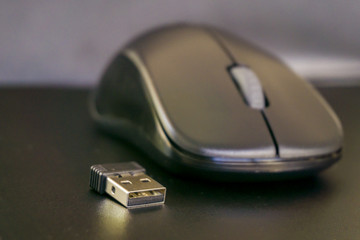 Close up of black wireless laptop mouse with USB transciever device. Computer accessories, wireless technology and portability concept. 