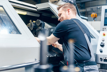 experienced worker changing tool setup of lathe machine