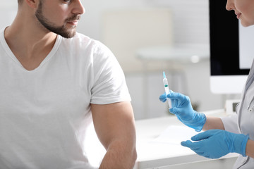 Wall Mural - Doctor giving injection to patient in hospital, closeup. Vaccination concept