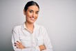 © Krakenimages.com - Young beautiful brunette woman wearing casual shirt over isolated white background happy face smiling with crossed arms looking at the camera. Positive person.