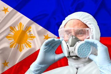 male doctor, disinfector in a protective suit, respirator, glasses on the background of the philippines silk national flag, biological and chemical weapons concept, coronavirus, COVID-19