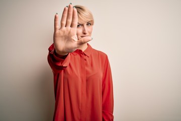 Sticker - Young beautiful business blonde woman with short hair standing over isolated background doing stop sing with palm of the hand. Warning expression with negative and serious gesture on the face.