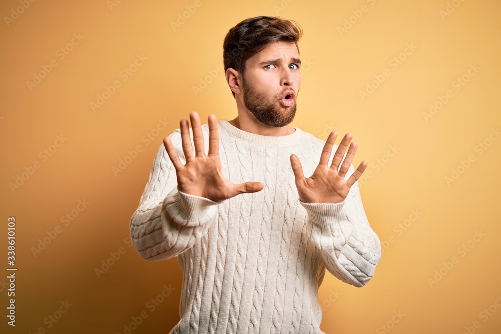 Young blond man with beard and blue eyes wearing white sweater over ...