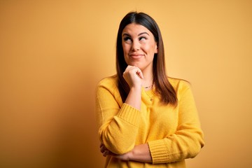 Sticker - Young beautiful woman wearing casual sweater over yellow isolated background with hand on chin thinking about question, pensive expression. Smiling with thoughtful face. Doubt concept.