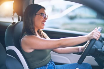 Young beautiful woman smiling happy  and confident. Sitting with smile on face driving a car