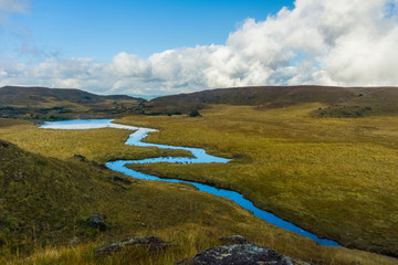 amazing landscape in the countryside with a stream flowing by and a vista view of the clouds and the mountains