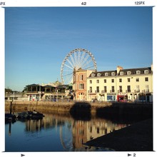 Torquay Harbor By City Buildings And Ferris Wheel Against Sky
