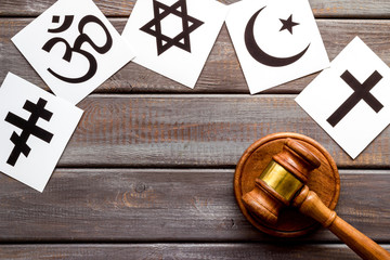 Religious conflict concept. World religions symbols near gavel on wooden background top view copy space