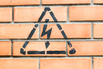 high voltage danger yellow sign on a brick wall building