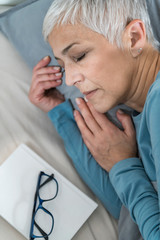 Wall Mural - Beautiful Senior Woman Sleeping Peacefully After Reading a Book