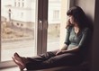 © Tunatura - Sad young woman sitting on the window at home isolated, watching out. Coronavirus quarantine concept.