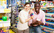 © JackF - Cheerful African man and European woman choosing pens and pencils in office supply shop