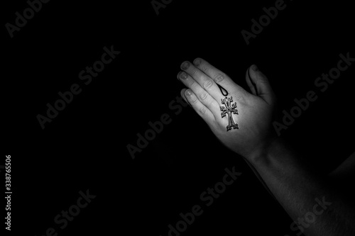 Praying hands with Celtic Cross in hand, beautiful light, asking for help, majestic lights, copy space, black and white.