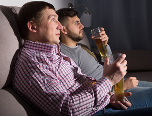 Canvas Print - Two men watching tv on sofa with beer