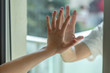 © gdefilip - Hands separated by a glass window for social distancing during the corona virus lockdown