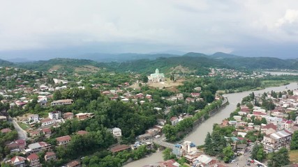 Wall Mural - flight over the city of Kutaisi, Georgia. Bagrati's Cathedral and River Rioni and old houses with Red roofs. Mountains in the distance.