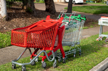 Abandoned shopping trolleys on a green grass near the pathway on a suburb street