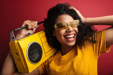 Wall Mural - Image of african american woman laughing and holding vintage boombox