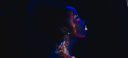 Wall Mural - side view on beautiful young woman with fluorescent prints on face, unusual prints, body art. neon lights, uv ray, luminescence concept