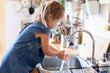 Kid washing hands at home under water tap. Cute child girl in flour after cooking in cozy kitchen. Food safety, infection prevention. Avoid spreading viruses and germs.