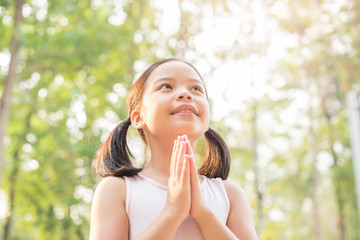 Wall Mural - cute little girl hands praying to god with the bible in the morning on nature background.  little asian girl hand praying for thank god. copy space. spirituality and religion faith hope concept.