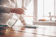 © Алина Троева - Close up of cleaning home wood table, sanitizing kitchen table surface with disinfectant antibacterial spray bottle, washing surfaces with towel and gloves. COVID-19 prevention sanitizing inside.