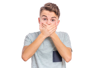 Wall Mural - Portrait of amazed teen boy covers mouth with hands. Child with in surprise or fright looking at camera. Caucasian cute young teenager, isolated on white background. Speak no evil concept.