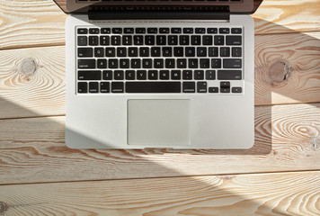 Poster - Top view of laptop on loft-style table in sunny day. Coworking or working at home concept image.