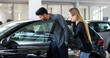 © Minerva Studio - Young couple choosing new car for buying in dealership shop