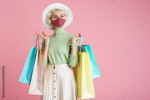 Cuadros en Lienzo Spring shopping during quarantine conception: fashionable woman wearing protective mask posing with colorful paper bags