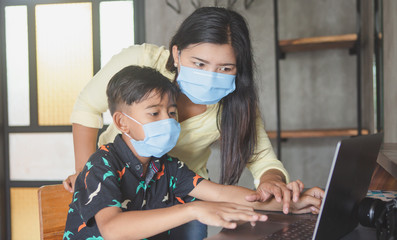 Lockdown and school closures. Mother helping her child with face mask studying online classes at home. Quarantine, self-isolation, online education concept, home schooler during COVID-19 pandemic