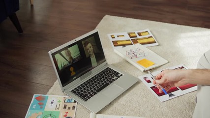 Wall Mural - tilt down shot of young man discussing ideas with two male colleagues during video call on laptop co