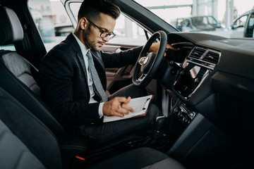 Poster - Car seller working in showroom and quality control checking of car details for the last time before buyer comes.