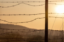 Sunrise Behind A Barbed-wire Fence. Ranch Fence At Golden Hour