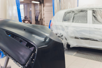 Auto mechanic preparing the car for paint job by applying polish with the power buffer machine