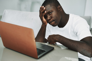 A man at home on the couch in front of a laptop