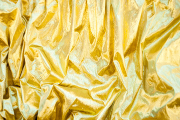 Full frame background of shimmery gold fabric with textured rumples and wrinkles