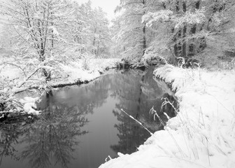 A small creek flows through a landscape blanketed with the first winter snowfall of the year.