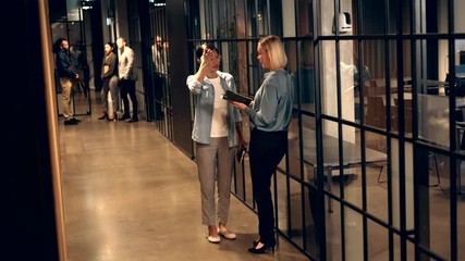 Wall Mural - Smiling businesswoman
talking together in an office
hallway