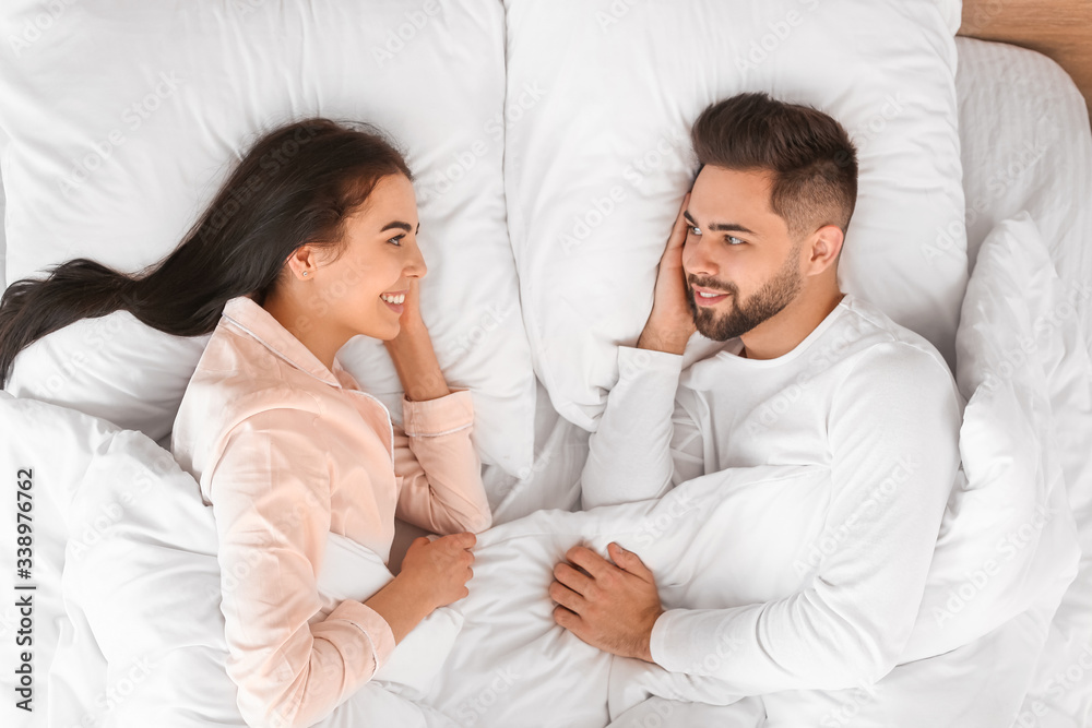 Happy young couple lying in bed at home
