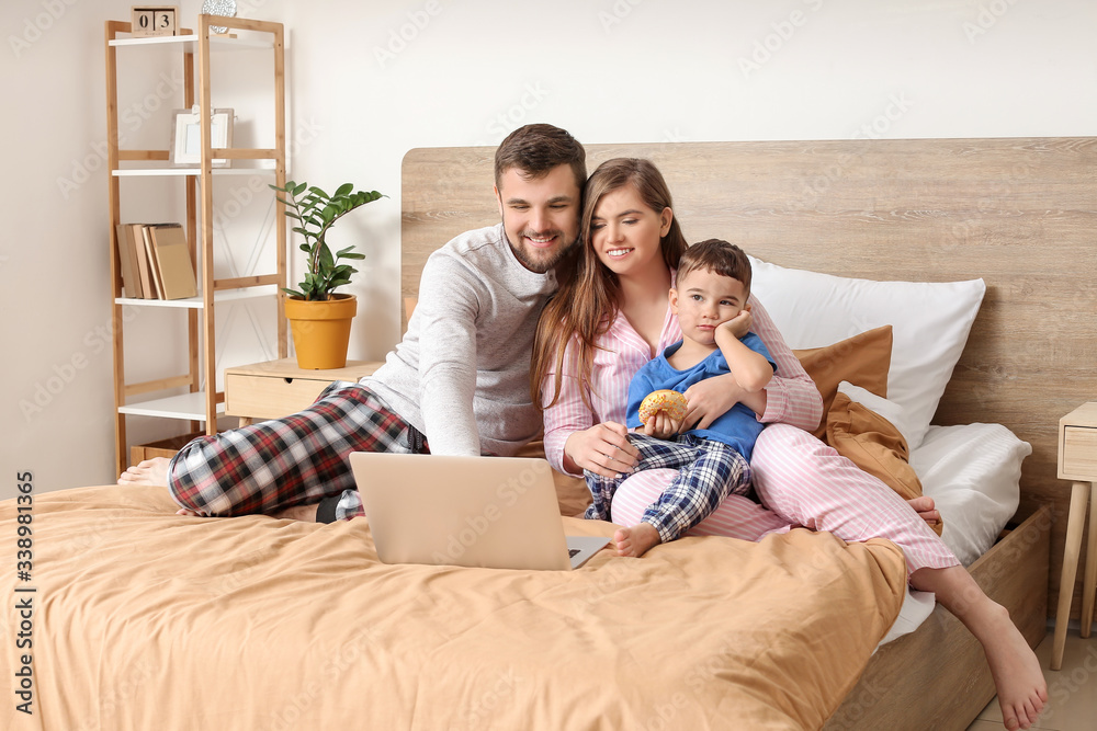 Happy family using laptop in bedroom