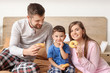 © Pixel-Shot - Happy family eating donuts in bedroom