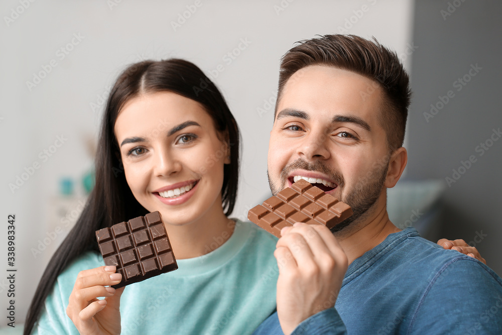 Beautiful young couple eating chocolate at home