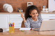 © Pixel-Shot - Little African-American girl doing homework in kitchen