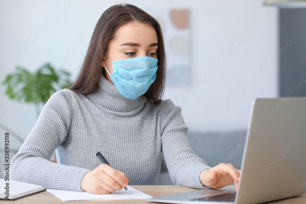 Young woman wearing medical mask while working in office