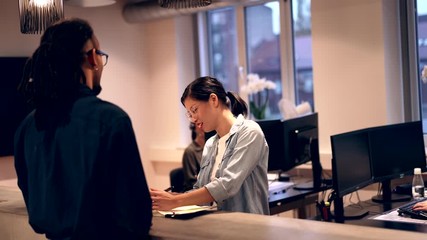 Wall Mural - Smiling Asian
businesswoman talking with
a colleague in an office